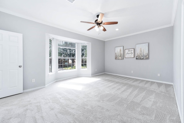 carpeted spare room featuring ceiling fan and crown molding