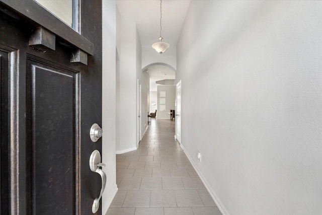 corridor with tile patterned floors and a high ceiling