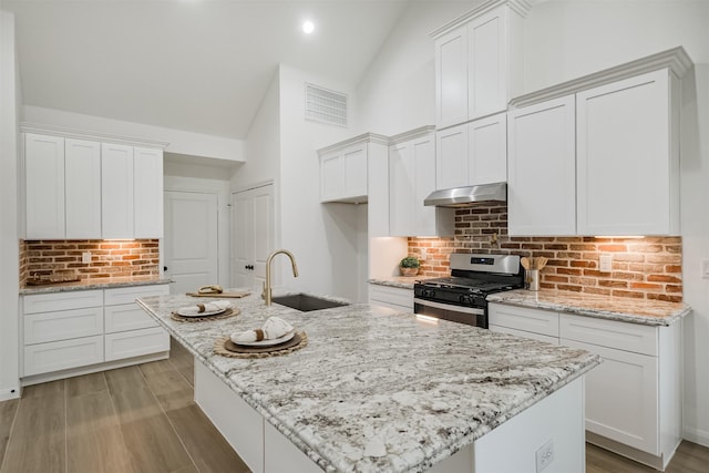 kitchen featuring gas range, a center island with sink, tasteful backsplash, and sink