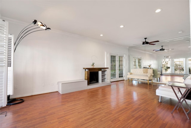 unfurnished living room with wood-type flooring, ceiling fan, and crown molding