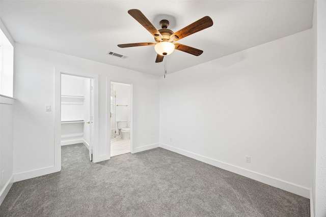 unfurnished bedroom featuring carpet floors, a spacious closet, ceiling fan, ensuite bath, and a closet