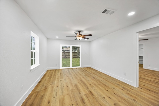 empty room with ceiling fan and light hardwood / wood-style flooring