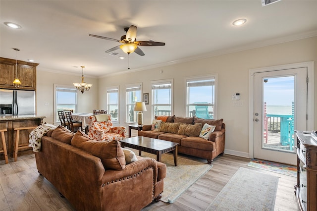 living room with a wealth of natural light, light hardwood / wood-style floors, and ceiling fan with notable chandelier