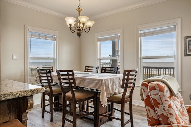 dining area featuring a chandelier, light wood-type flooring, a water view, and ornamental molding