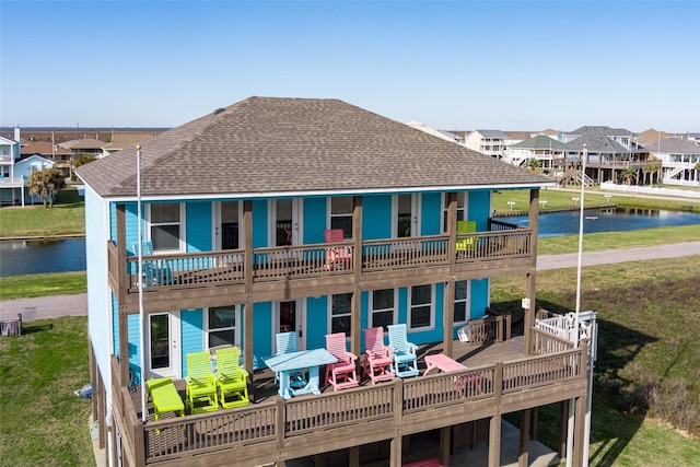 back of house featuring a lawn and a deck with water view