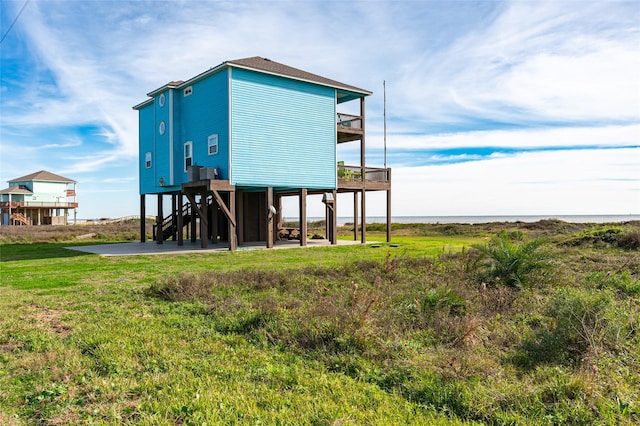 back of house with a yard, a balcony, and a water view