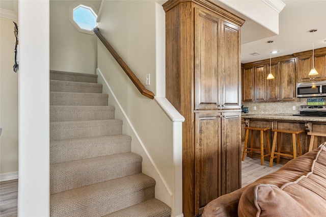 stairs with crown molding and wood-type flooring