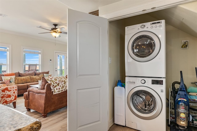 laundry area with ceiling fan, light hardwood / wood-style floors, crown molding, and stacked washer / dryer