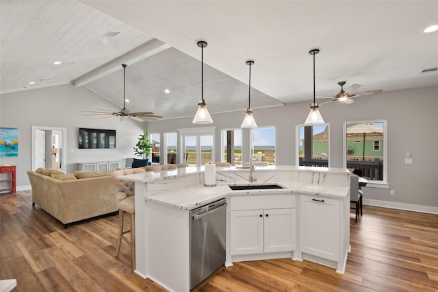 kitchen with a kitchen island with sink, sink, stainless steel dishwasher, light stone countertops, and white cabinetry