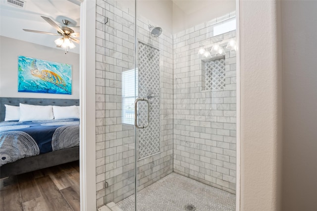 bathroom with hardwood / wood-style floors, ceiling fan, and a shower with shower door