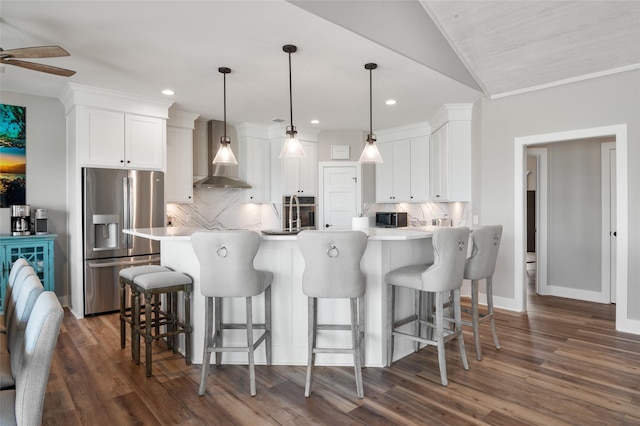 kitchen featuring white cabinets, stainless steel fridge with ice dispenser, decorative light fixtures, and wall chimney range hood