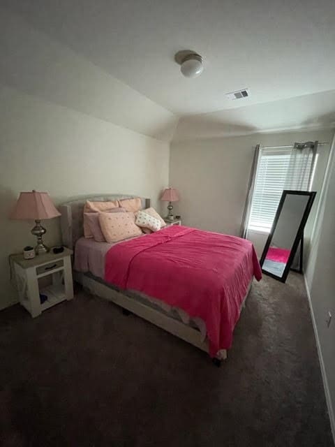 bedroom featuring lofted ceiling and dark carpet