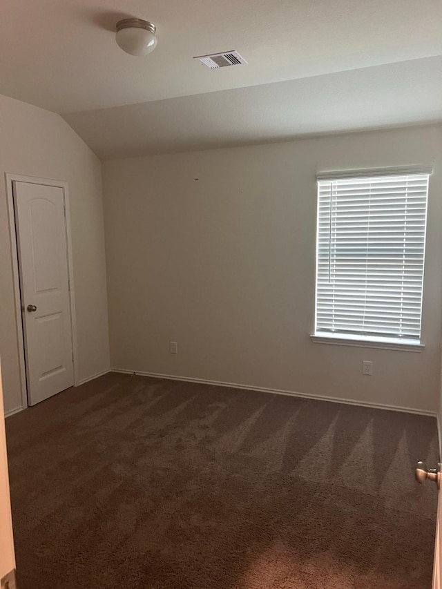 carpeted empty room featuring lofted ceiling