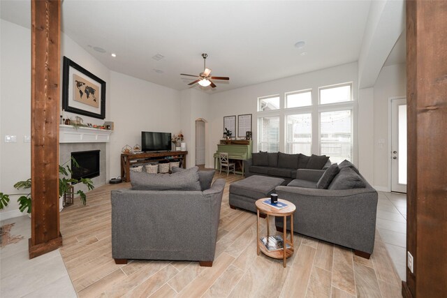 living room with ceiling fan and a tiled fireplace