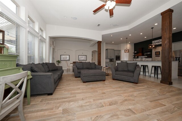 living room featuring ceiling fan, light hardwood / wood-style floors, and decorative columns