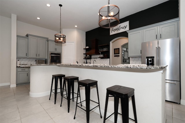 kitchen featuring appliances with stainless steel finishes, tasteful backsplash, light stone counters, and gray cabinetry