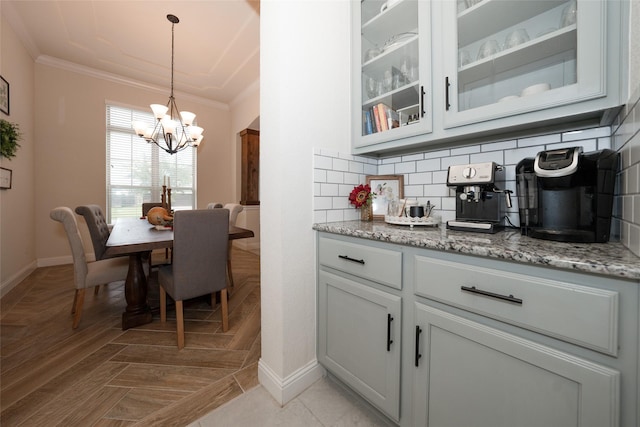 dining space with light parquet floors, crown molding, and an inviting chandelier