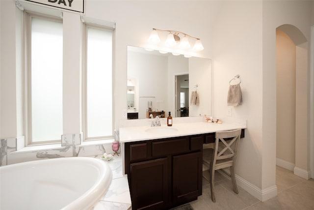 bathroom with tile patterned floors, tiled tub, and vanity