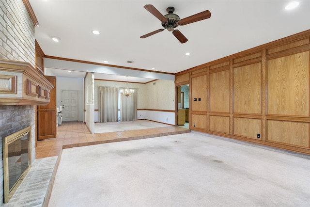 unfurnished living room featuring ceiling fan with notable chandelier, a fireplace, ornamental molding, and light tile patterned floors