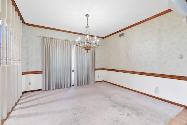 spare room featuring light colored carpet, ornamental molding, and a chandelier