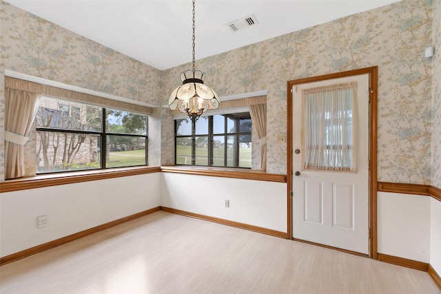 unfurnished dining area featuring a notable chandelier and wood-type flooring