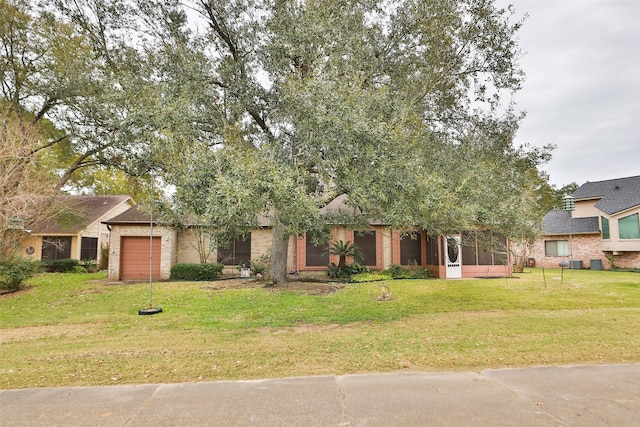 obstructed view of property with a sunroom, a front lawn, and a garage