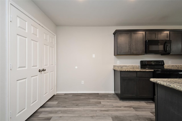 kitchen featuring black appliances, light stone counters, dark brown cabinetry, and light wood-type flooring