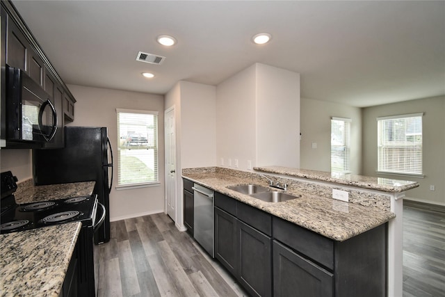 kitchen featuring sink, light hardwood / wood-style flooring, light stone counters, and black appliances