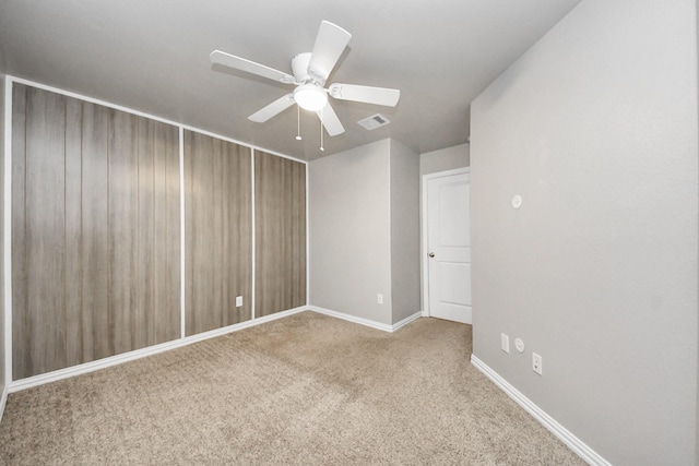 unfurnished room with ceiling fan and carpet