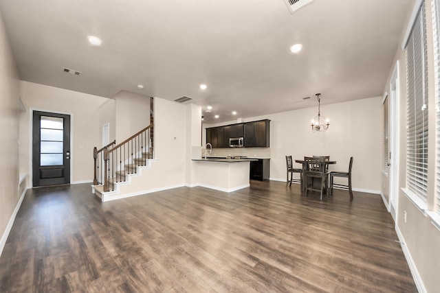 unfurnished living room with dark wood-type flooring, sink, and a notable chandelier