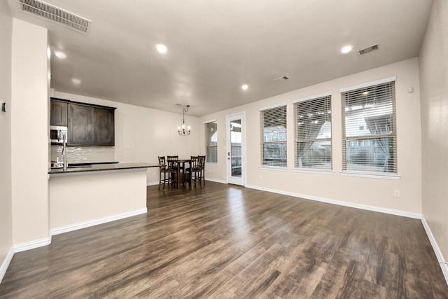 unfurnished living room featuring an inviting chandelier and dark hardwood / wood-style flooring