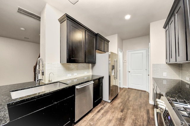 kitchen with sink, wood-type flooring, stainless steel appliances, and dark stone counters