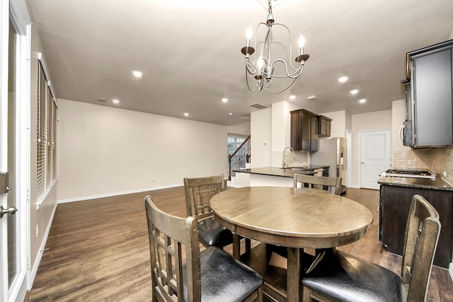 dining room featuring sink, a chandelier, and dark hardwood / wood-style flooring