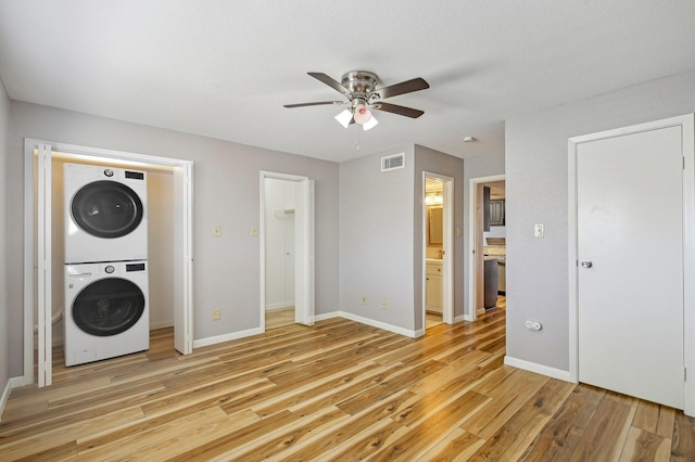 washroom featuring light wood finished floors, visible vents, stacked washing maching and dryer, laundry area, and baseboards