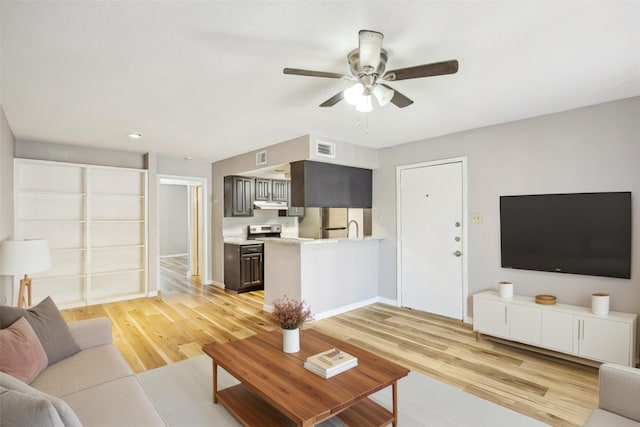 living room featuring a ceiling fan, visible vents, light wood-style flooring, and baseboards