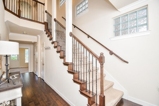 stairway featuring a high ceiling, hardwood / wood-style flooring, and ornamental molding