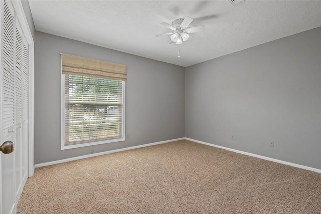 carpeted empty room with ceiling fan and a textured ceiling