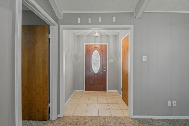 foyer featuring ornamental molding, a textured ceiling, light colored carpet, wooden walls, and beamed ceiling