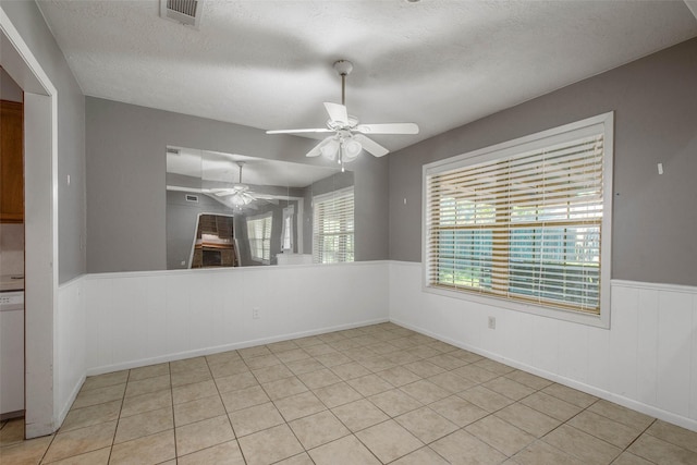 tiled empty room featuring ceiling fan and a textured ceiling