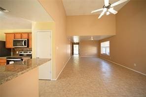 kitchen featuring ceiling fan, light stone countertops, lofted ceiling, and appliances with stainless steel finishes