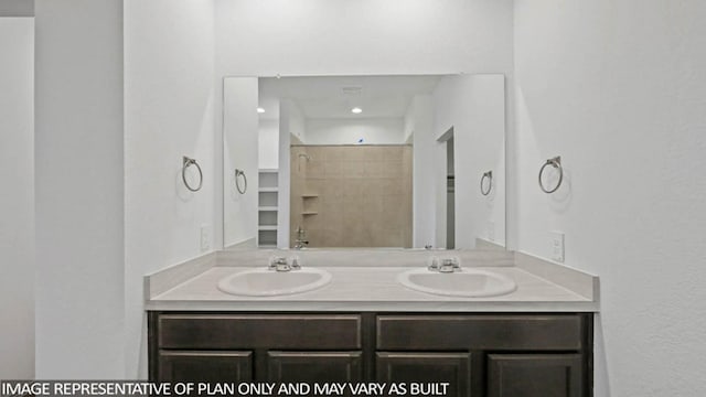 bathroom featuring a tile shower and vanity