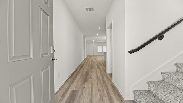corridor featuring visible vents, baseboards, recessed lighting, stairway, and light wood-style flooring