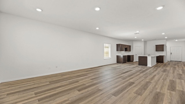unfurnished living room featuring recessed lighting, light wood finished floors, and baseboards