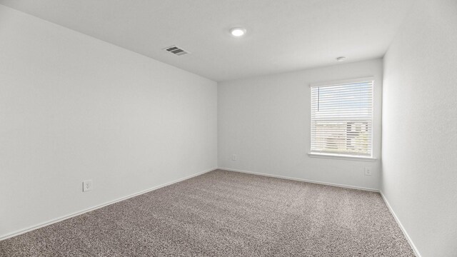 carpeted spare room featuring visible vents and baseboards