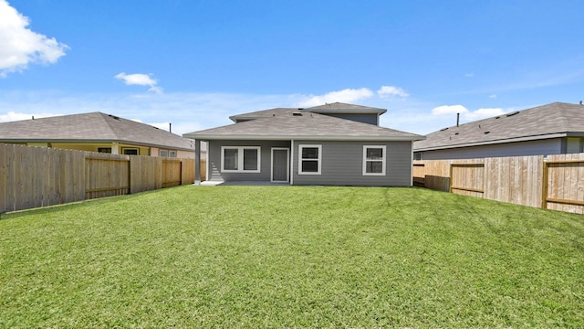 rear view of house featuring a yard and a fenced backyard