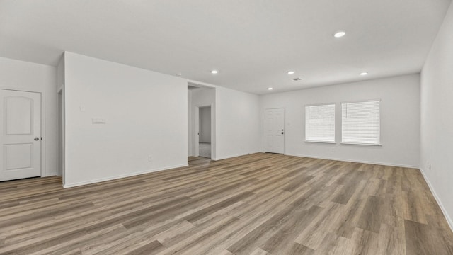 unfurnished living room featuring light wood-type flooring, recessed lighting, and baseboards