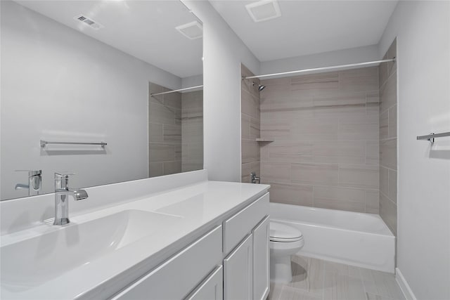 full bathroom with tiled shower / bath, tile patterned flooring, vanity, and toilet