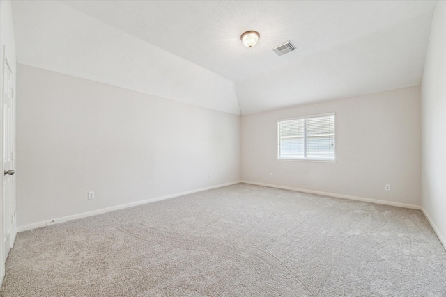 spare room featuring light colored carpet and lofted ceiling