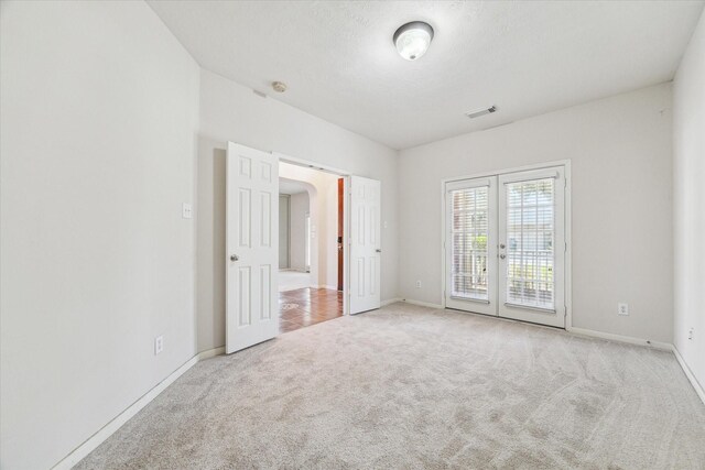 unfurnished room with light carpet and french doors