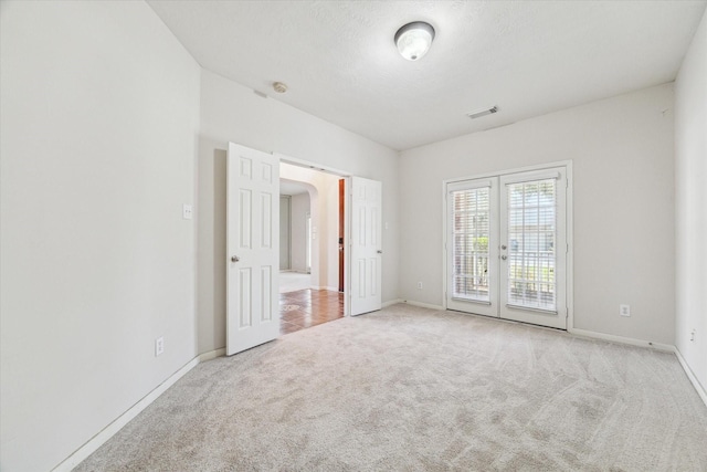 carpeted spare room with french doors